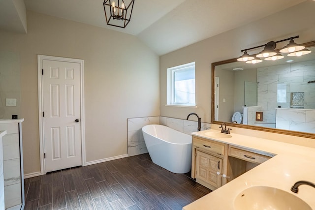 bathroom featuring double vanity, vaulted ceiling, a freestanding tub, and a sink