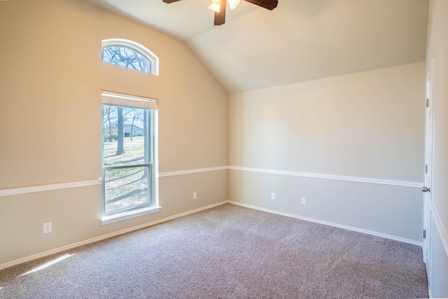 carpeted spare room with vaulted ceiling, a ceiling fan, and baseboards