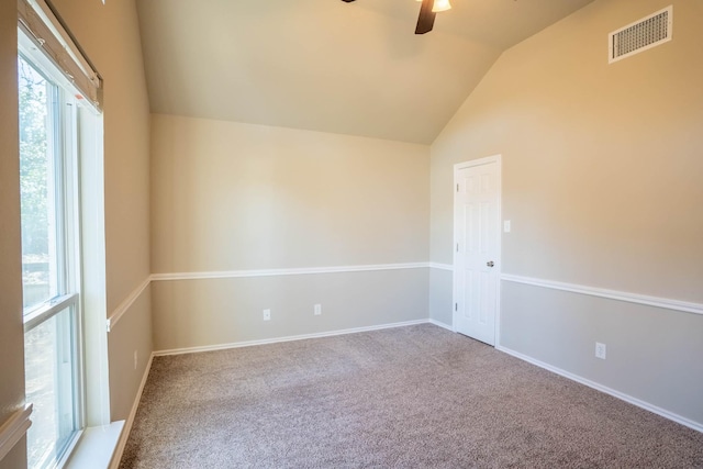 empty room with a wealth of natural light, visible vents, lofted ceiling, and a ceiling fan