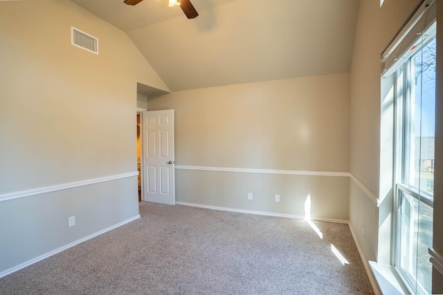 spare room with lofted ceiling, carpet flooring, visible vents, and ceiling fan