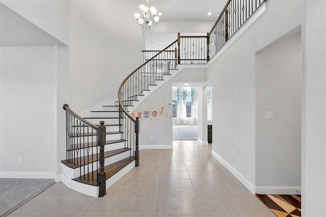 tiled foyer featuring stairs, an inviting chandelier, a high ceiling, and baseboards