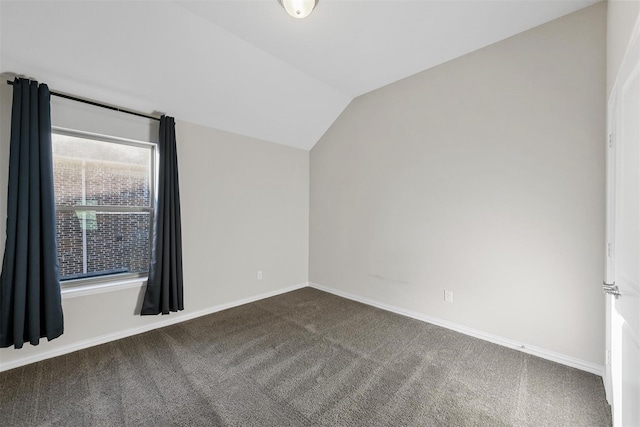 carpeted spare room with baseboards and lofted ceiling