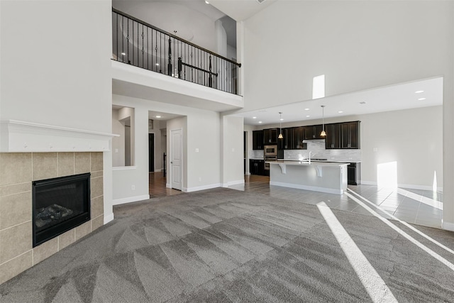 unfurnished living room with baseboards, light colored carpet, and a tile fireplace