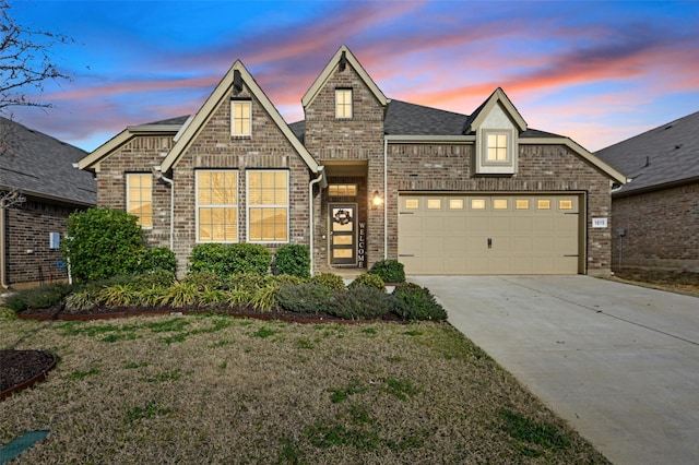 view of front of property with a lawn, driveway, roof with shingles, a garage, and brick siding