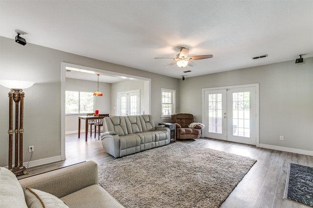 living room with baseboards, visible vents, ceiling fan, light wood-style floors, and french doors