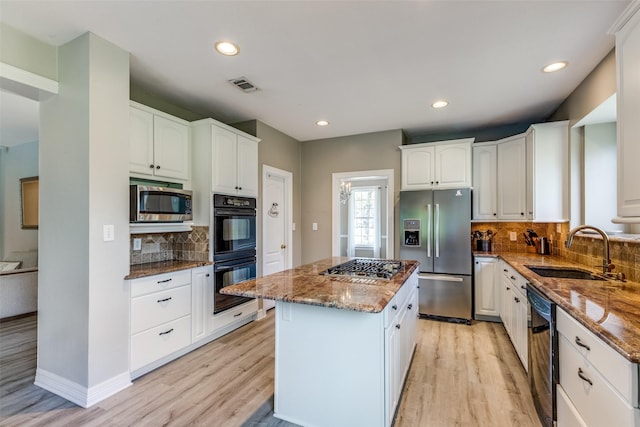 kitchen featuring a sink, visible vents, black appliances, and dark stone counters