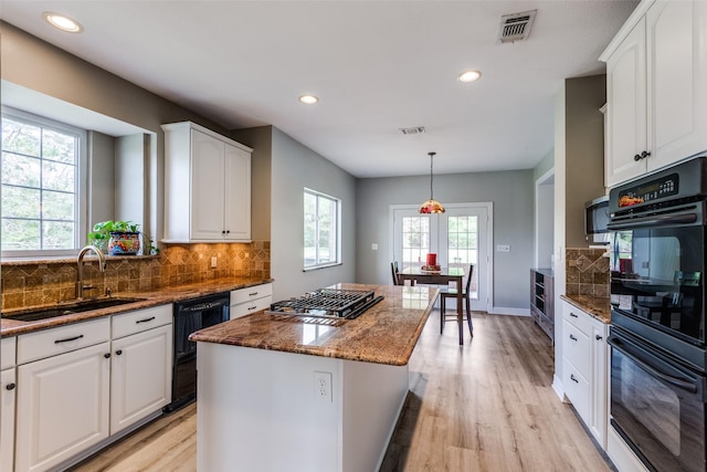 kitchen featuring black appliances, dark stone counters, visible vents, and a sink