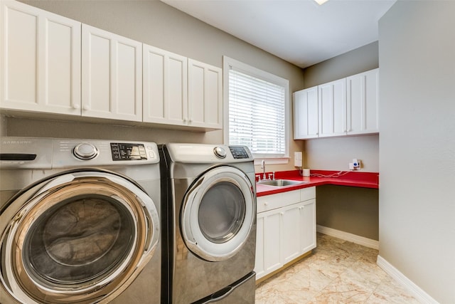 washroom with a sink, baseboards, cabinet space, and washing machine and dryer