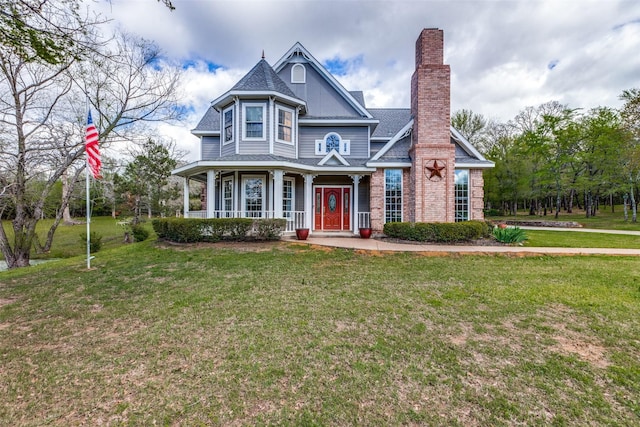 view of front of house featuring a chimney, a porch, a shingled roof, and a front lawn