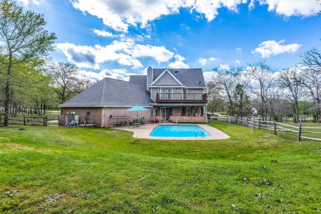 rear view of property with fence, a yard, a fenced in pool, brick siding, and a patio area