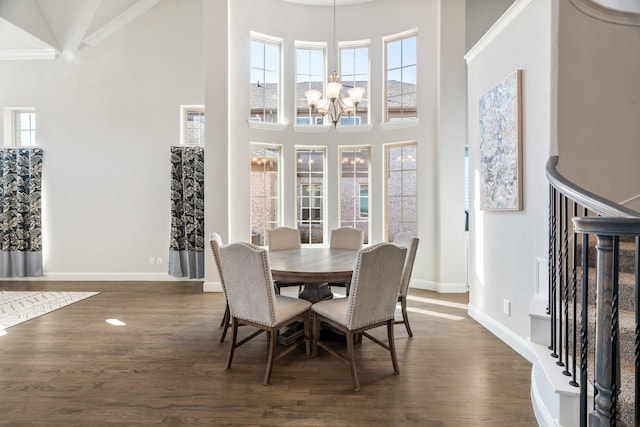 dining room featuring dark wood-type flooring, baseboards, a chandelier, stairs, and a towering ceiling