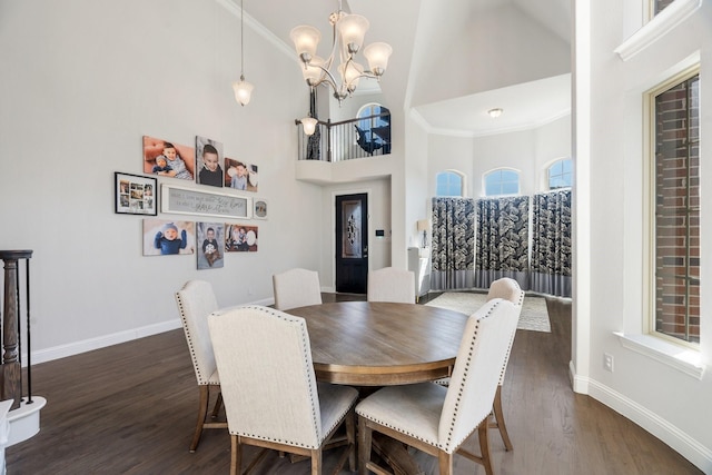 dining space with baseboards, dark wood-type flooring, an inviting chandelier, and a towering ceiling