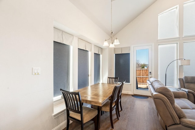 dining space featuring dark wood finished floors, a chandelier, high vaulted ceiling, and baseboards