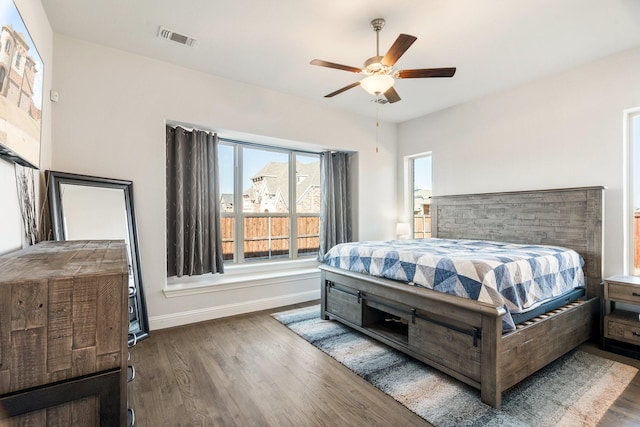 bedroom with ceiling fan, wood finished floors, visible vents, and baseboards