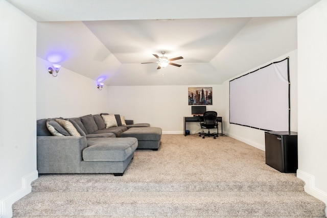 carpeted cinema with a raised ceiling, baseboards, and ceiling fan