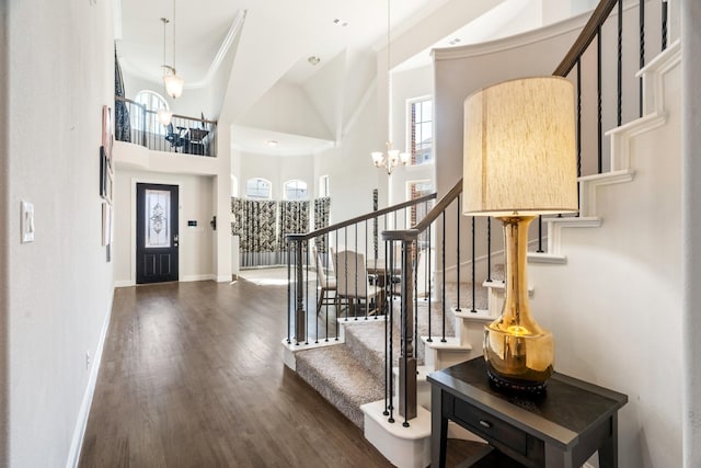 entrance foyer featuring baseboards, an inviting chandelier, dark wood-style flooring, ornamental molding, and stairs