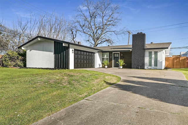 view of front of home with concrete driveway, a front yard, a garage, brick siding, and a chimney