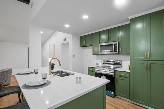 kitchen featuring green cabinets, recessed lighting, light wood-style floors, stainless steel appliances, and a sink