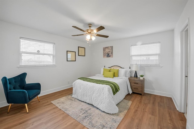 bedroom with multiple windows, light wood-style floors, and baseboards