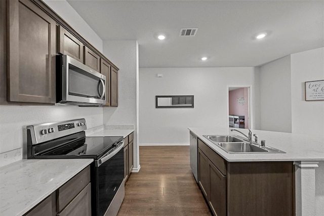 kitchen featuring visible vents, an island with sink, a sink, dark brown cabinetry, and appliances with stainless steel finishes