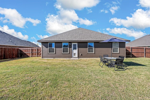 rear view of house featuring a fenced backyard, a lawn, and roof with shingles