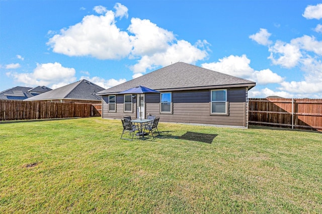 back of house featuring a fenced backyard, a lawn, and a shingled roof