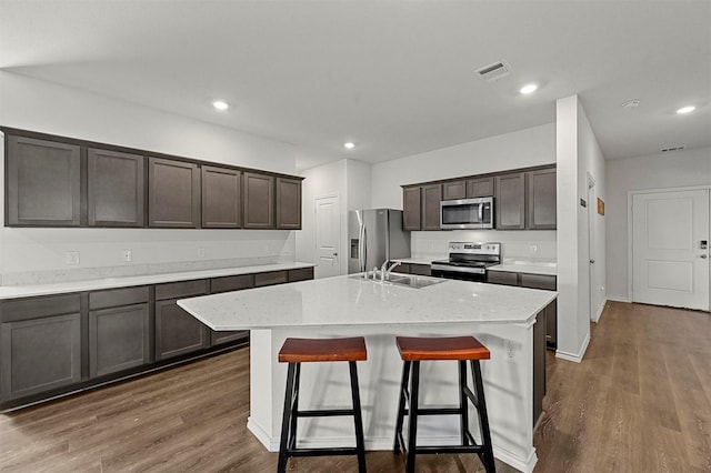 kitchen featuring visible vents, stainless steel appliances, dark wood-type flooring, and a sink