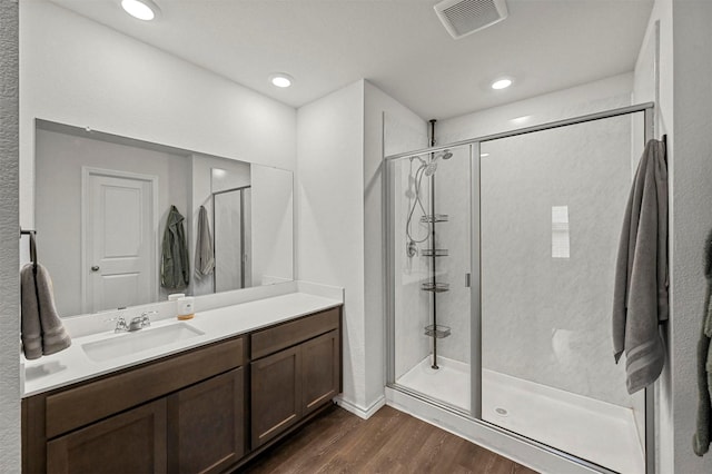 full bathroom with visible vents, a shower stall, vanity, and wood finished floors