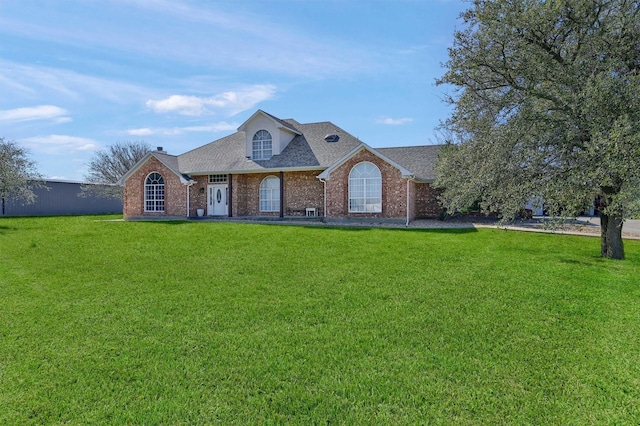 view of front of property featuring brick siding, roof with shingles, and a front yard