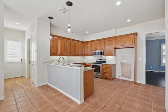 kitchen with visible vents, backsplash, appliances with stainless steel finishes, a peninsula, and brown cabinetry