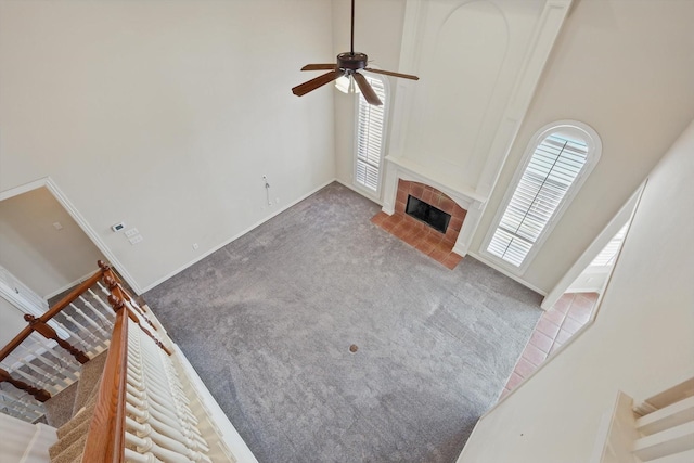 unfurnished living room with a wealth of natural light, carpet, a towering ceiling, and a tile fireplace