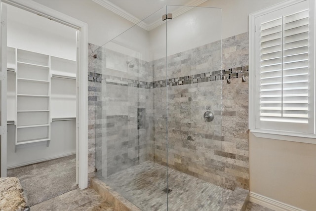 bathroom with a walk in closet, a stall shower, crown molding, and baseboards