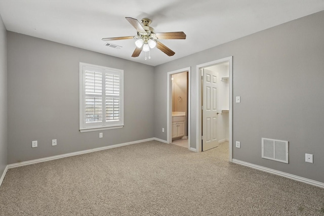 unfurnished bedroom with a walk in closet, baseboards, visible vents, and light carpet