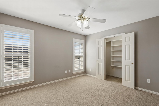 unfurnished bedroom with a spacious closet, a ceiling fan, baseboards, and carpet floors