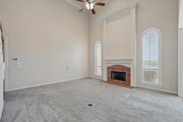 unfurnished living room with plenty of natural light, carpet floors, a ceiling fan, and a tiled fireplace