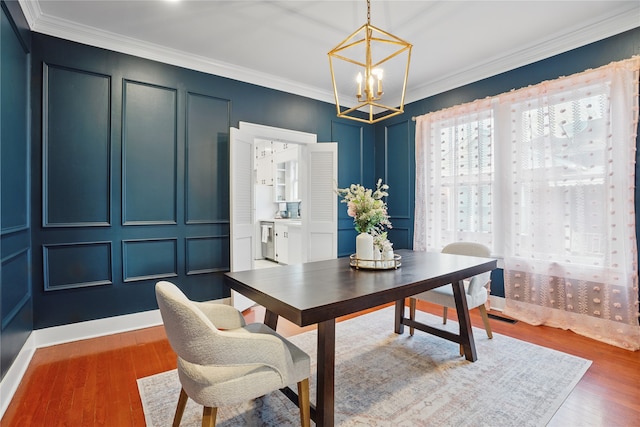 office space featuring a decorative wall, crown molding, an inviting chandelier, and wood finished floors