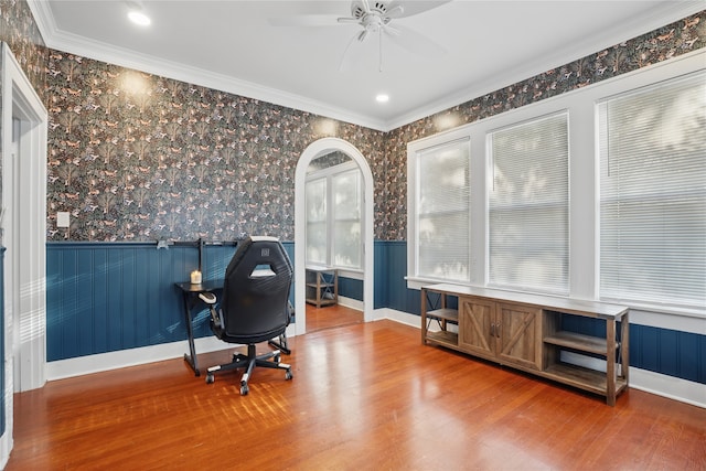 office area with ornamental molding, wood finished floors, wainscoting, wallpapered walls, and ceiling fan