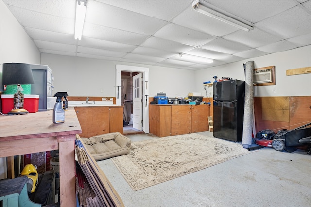 miscellaneous room with a drop ceiling, a wall mounted air conditioner, concrete floors, and a sink