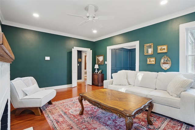 living room featuring ornamental molding, light wood-style floors, baseboards, and ceiling fan