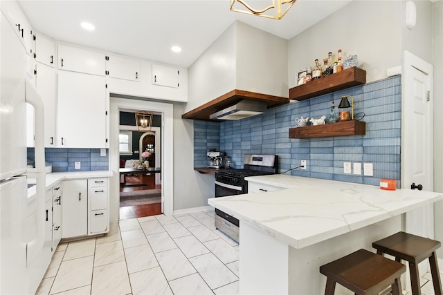 kitchen with a peninsula, freestanding refrigerator, an inviting chandelier, gas stove, and open shelves