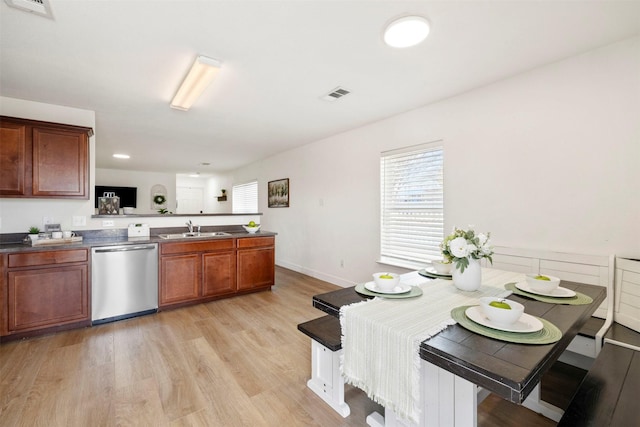 kitchen with a peninsula, light wood-style flooring, a sink, stainless steel dishwasher, and dark countertops