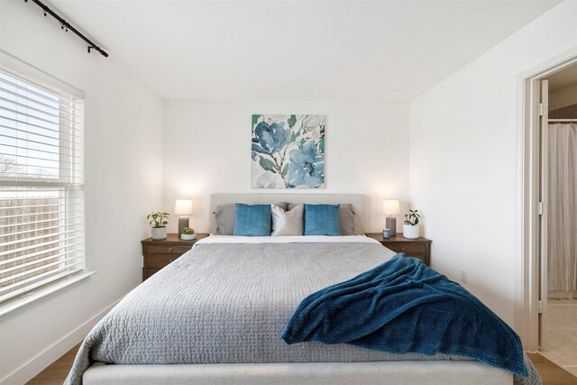 bedroom featuring baseboards, multiple windows, and wood finished floors