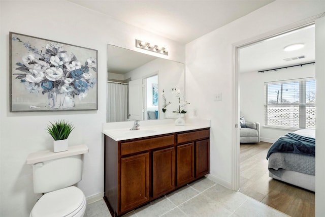 bathroom featuring visible vents, baseboards, toilet, ensuite bathroom, and vanity