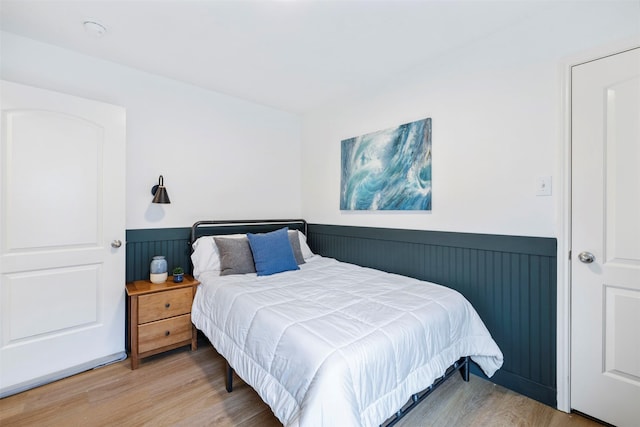 bedroom with wood finished floors and wainscoting