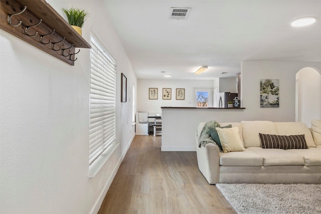 living area featuring arched walkways, visible vents, baseboards, and wood finished floors