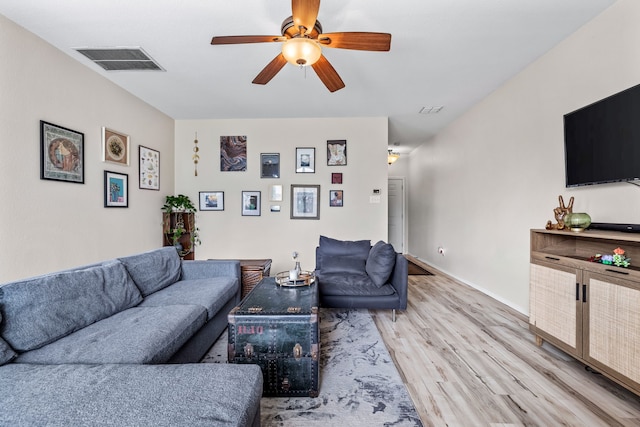 living area with light wood-type flooring, visible vents, baseboards, and a ceiling fan