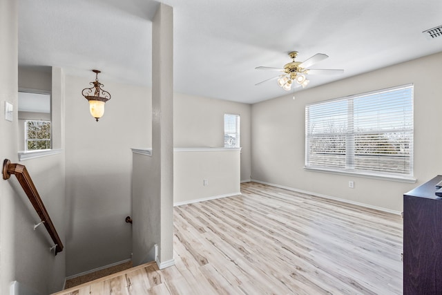 unfurnished room with visible vents, baseboards, wood finished floors, and a ceiling fan