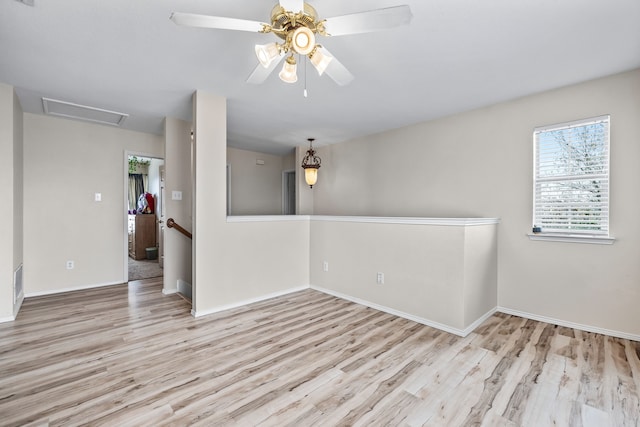 unfurnished room featuring ceiling fan, baseboards, attic access, and wood finished floors