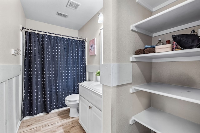 bathroom featuring curtained shower, toilet, wood finished floors, and visible vents