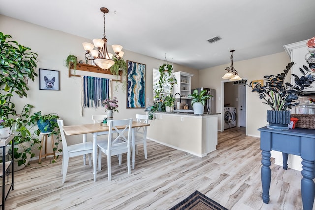 dining area featuring visible vents, baseboards, washing machine and dryer, light wood-type flooring, and an inviting chandelier